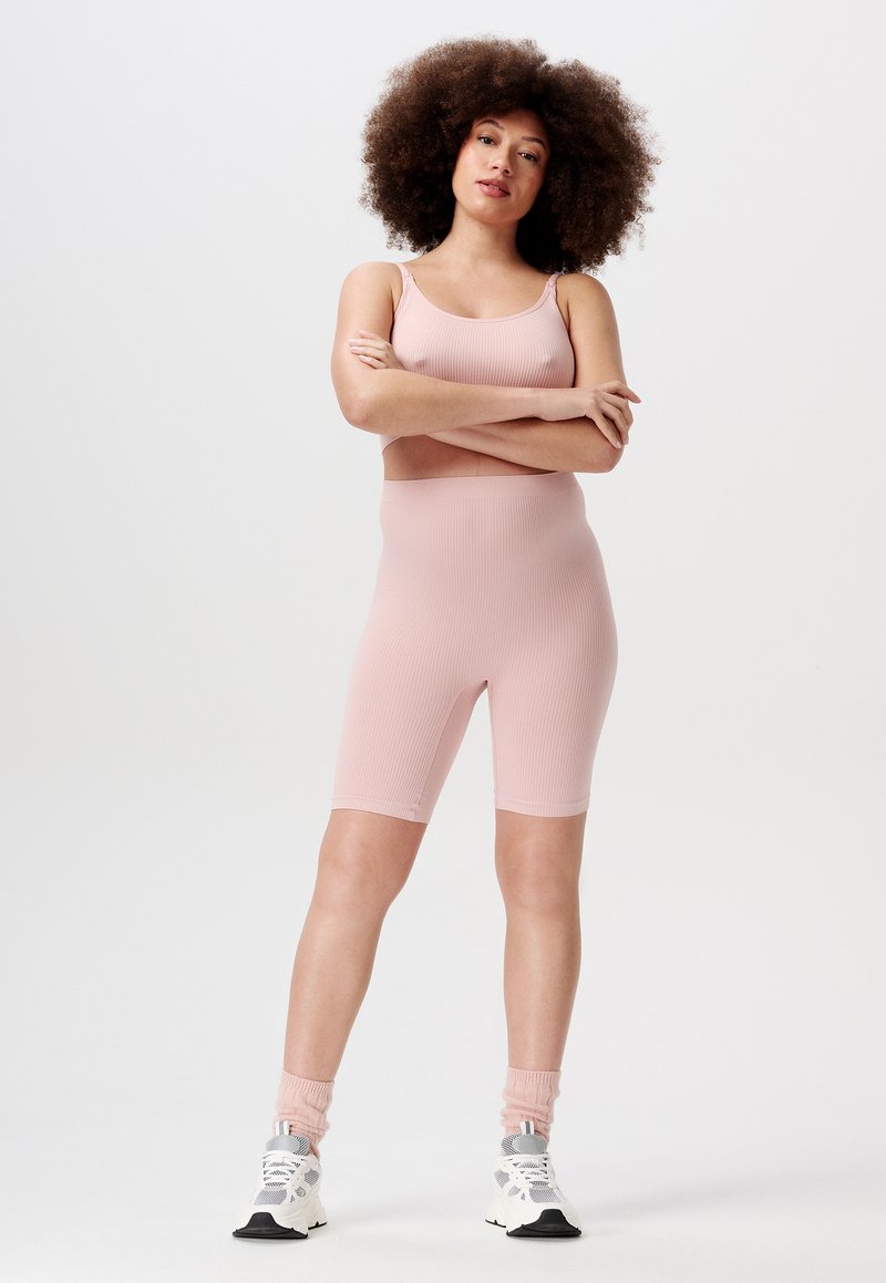 Lichtroze geribbelde bodysuit met spaghettibandjes en een lengte tot halverwege de dijen. Gekocht met witte sneakers en roze enkelkousen.