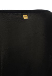 Tessuto nero con superficie testurizzata, caratterizzato da un piccolo etichetta dorata incastonata al centro in alto, che indica il nome del marchio.