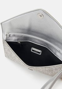 Silver clutch bag featuring a smooth metallic interior, a zip pocket, textured exterior with glittering accents, and a snap closure.
