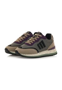 Zapatillas en tonos beige y negro con acentos morados, fabricadas en un tejido texturizado y suelas moteadas. Cuentan con un diseño de cordones y un detalle de logo prominente.