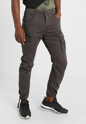 Cargo pants in donkergrijs katoenmix, met meerdere zakken, elastische boorden en een slim fit ontwerp. Gedragen met zwarte sneakers.