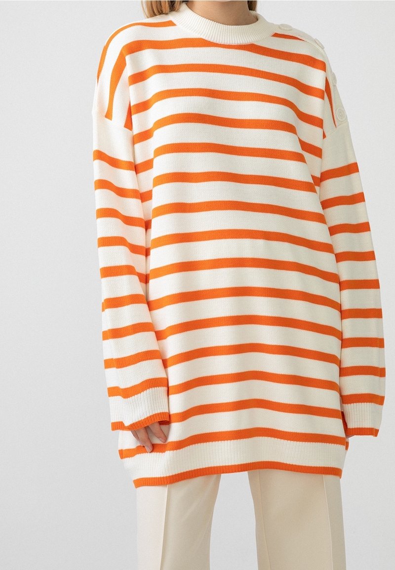 Übergroßer Strickpullover mit auffälligen orangen und weißen horizontalen Streifen, Rundhalsausschnitt und gerippten Bündchen. Dekorative Knöpfe auf der linken Schulter.