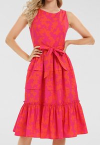 Robe rose vif avec motif floral orange, sans manches, design à volants, ceinture en tissu à la taille, détail de ourlet à volants.