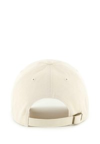 Beige cotton baseball cap with a curved brim, adjustable strap at the back, and ventilation holes on the side. Textured fabric.