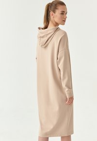 Abito beige con cappuccio, maniche lunghe, vestibilità comoda e lunghezza fino al polpaccio. Tessuto liscio con un design minimalista e senza motivi visibili.