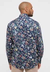 Bloemenduik met een donker marineblauwe achtergrond en meerkleurige bloemen en bladeren, lange mouwen en een ontwerp op de achterkraag.