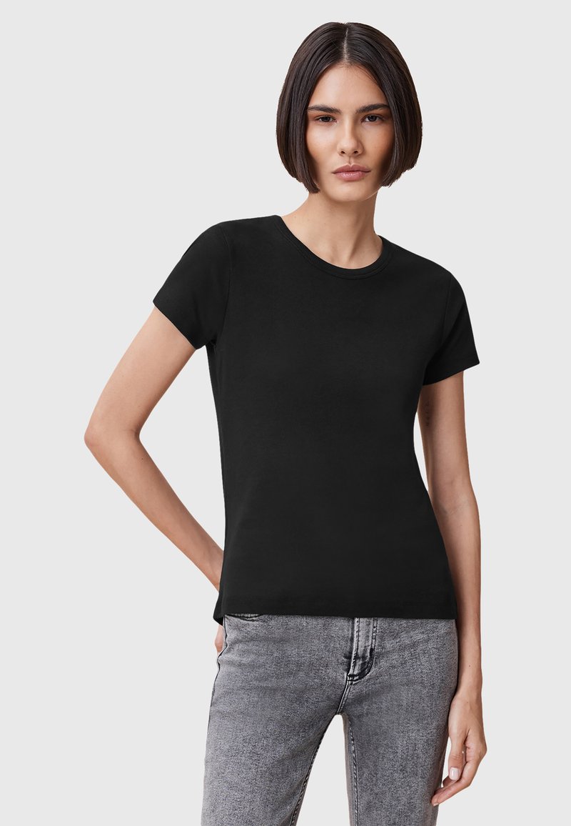 T-shirt nera in cotone con maniche corte e scollo rotondo, caratterizzata da un design aderente abbinato a pantaloni in denim grigio. Texture liscia e uniforme.
