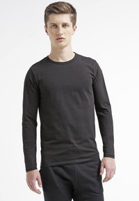 Sort langærmet T-shirt med rund hals fremstillet af bomuldsstof. Slim fit med glat tekstur og uden synlige mønstre eller udsmykninger.