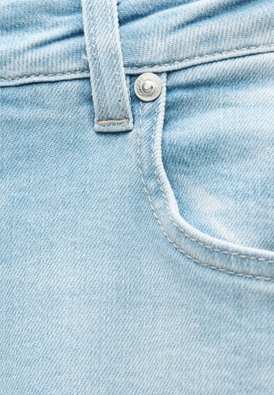 Ανοικτού μπλε τζιν με θηλιά για ζώνη, μεταλλικό καρφί και ραμμένη καμπυλωτή άκρη τσέπης σε κοντινή λήψη.