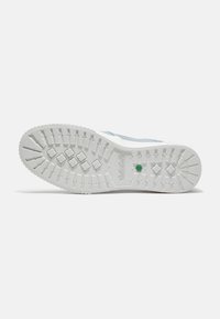 Suela de goma blanca con un patrón de agarre texturizado, con un acento verde. La parte superior del zapato es de color azul claro.