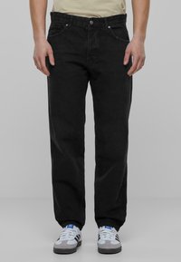 Blugi din denim negru cu un design cu pantaloni drepți, având cinci buzunare și accesorii metalice argintii. Materialul are o textură netedă și detalii minime.