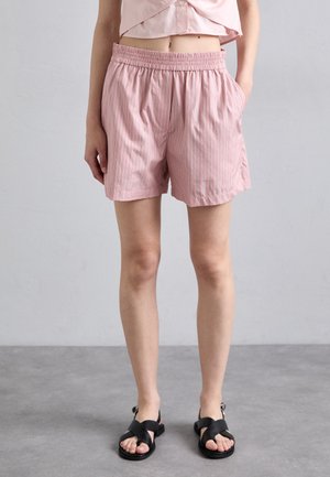 Rosa stripete shorts med elastisk midje og lommer, laget av lett stoff. Kombinert med svarte sandaler med stropper.