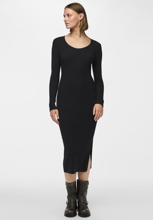 Rochie tricotată neagră cu mâneci lungi, decolteu în formă de ladă și slit lateral, făcută dintr-un material texturat. Asortată cu cizme din piele închise la culoare.