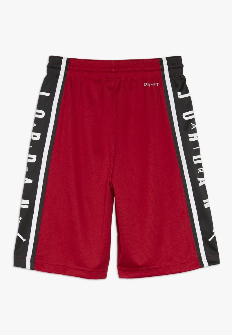 Shorts de sport rouges avec des panneaux latéraux noirs, ornés de lettres blanches, taille élastique et tissu respirant. Comprend des détails de marque.