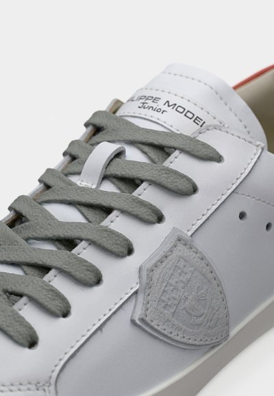 Baskets en cuir gris avec lacets gris, languette rembourrée et logo embossé sur le côté. Semelle en caoutchouc texturée et design minimaliste.