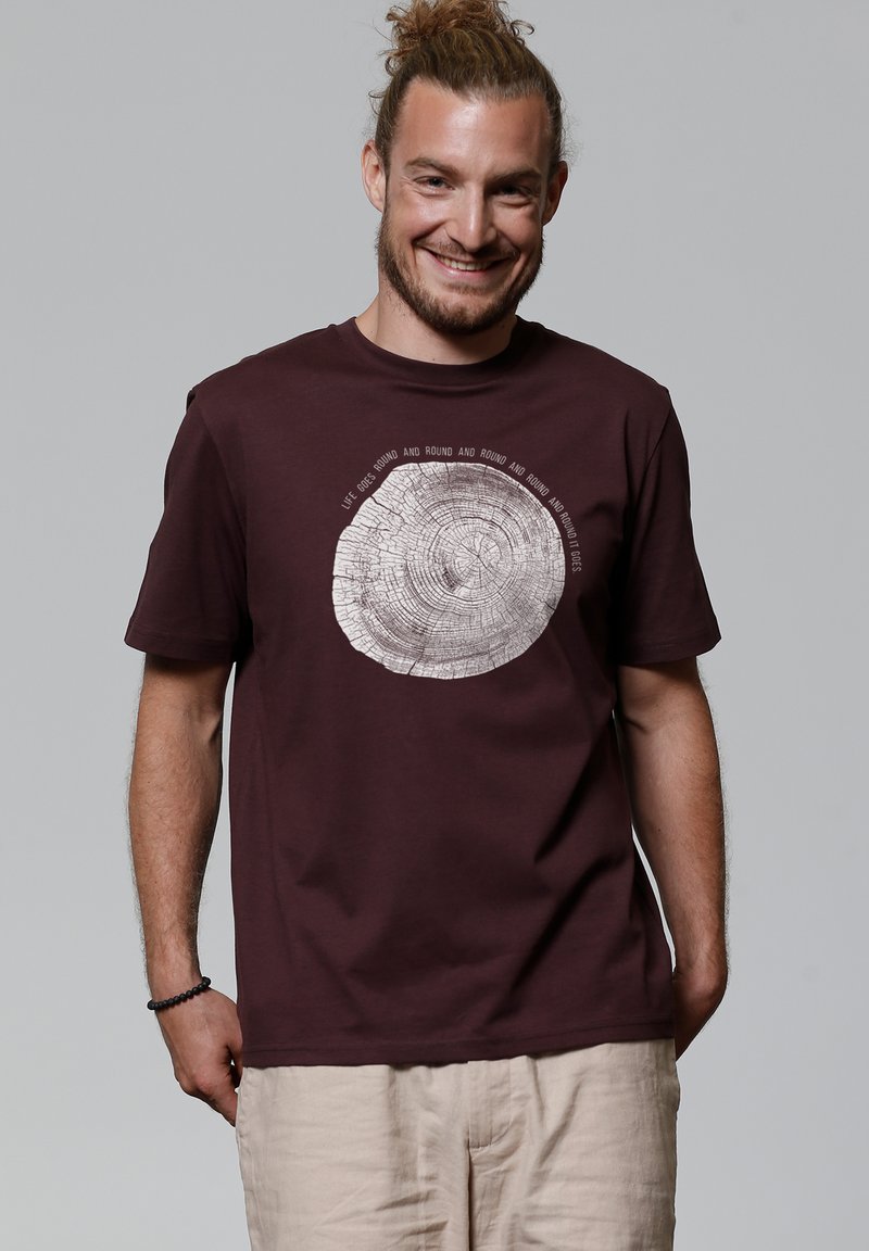Bordeaux T-shirt van katoen, met een cirkelvormige grafiek van een boomstam in het wit en tekst eromheen. Korte mouwen en een relaxte pasvorm.