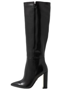 Knähög svart läderstövel med spetsig tå och tjock blockklack. Har en dragkedja på sidan och en slät yta med subtil lyster.