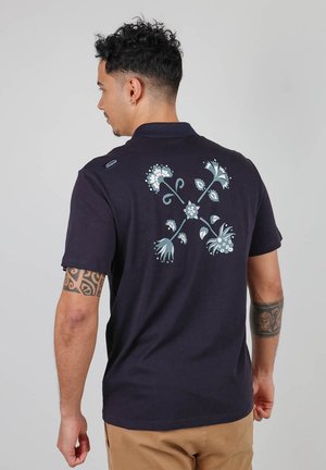 Polo shirt bleu marin à manches courtes, avec un motif floral en bleu clair au dos. Fabriqué en un mélange de coton lisse.