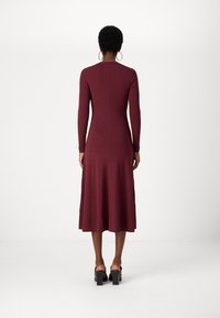Burgundi színű, bordázott, hosszú ujjú ruha, csinos felsőrésszel és bővülő szoknyával. Textúrált anyagból készült, kerek nyakkivágású és különleges hátkivágással rendelkezik.
