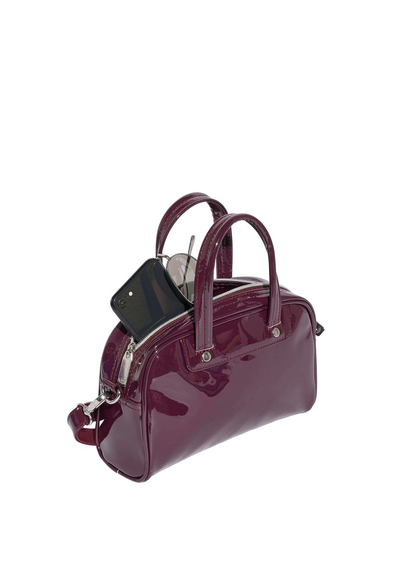 Borsa lucida di colore viola scuro con doppi manici, tasca superiore aperta contenente uno smartphone nero e occhiali rotondi.
