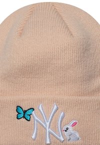 Gorro de punto en un suave color rubor, con un bordado de mariposa azul y acentos de conejo blanco, y un logotipo blanco en la parte frontal.