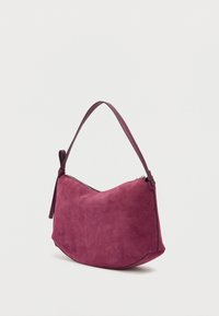 Sac à main en daim prune foncé avec une forme courbée, une bandoulière réglable et une fermeture éclair. Texture lisse avec des détails de design minimalistes.