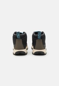 Zapatos medio-altos en negro y verde oliva con tejido texturizado, un acento azul intenso en la lengüeta del talón y una suela acolchada.