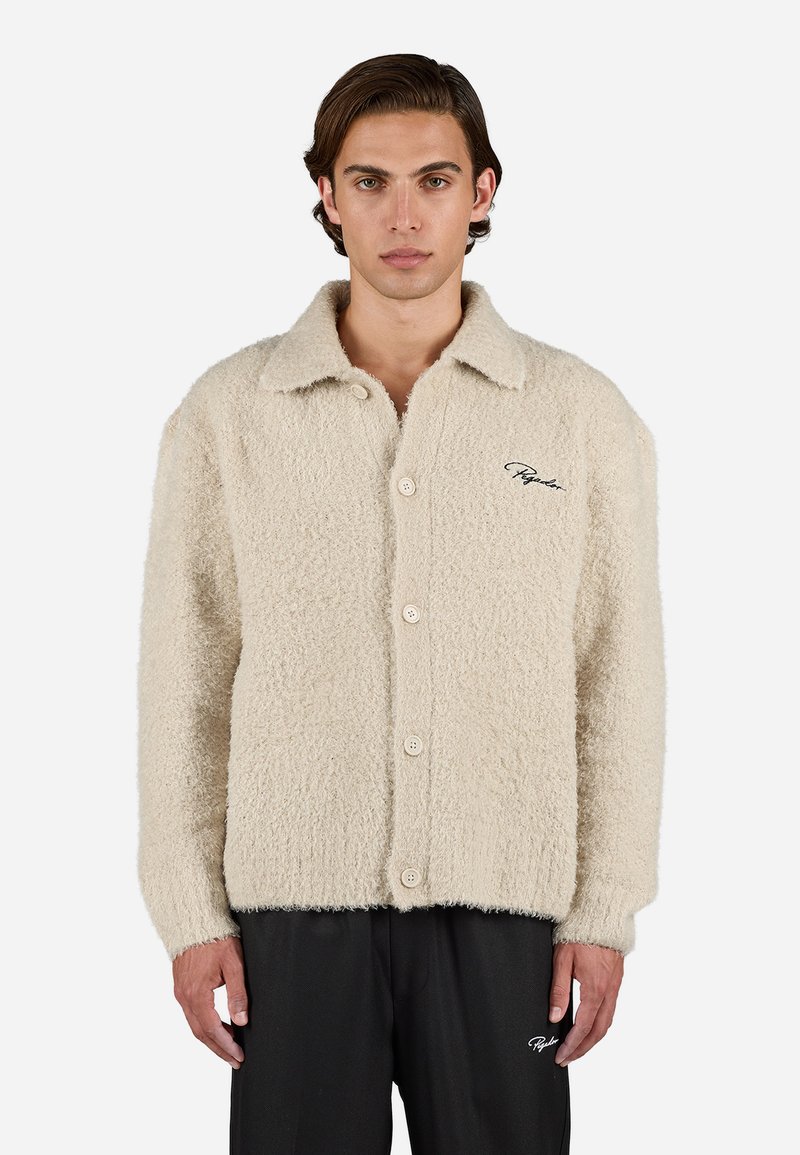 Beige, fluffy knap-shirt med spidse kraver og lange ærmer. Har fire knapper og et diskret broderet logo på brystet.