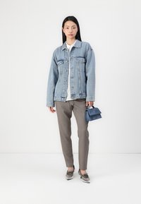 Denim jakna v svetlo modri barvi z gumbi spredaj, dvema prsoma; kombinirana z sivimi hlačami in temnomošnjim mini nahrbtnikom. Enostavna bela srajca spodaj.