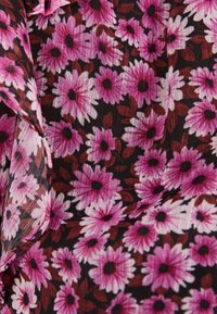 Przezroczysty materiał z gęsto skupionymi różowymi i białymi stokrotkami z ciemnymi środkami oraz rozsypanymi brązowymi liśćmi na czarnym tle.