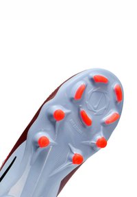 Sole di scarpe da calcio rossa e grigia con una base blu chiaro, caratterizzata da dettagli con tacchetti arancioni. Modello di grip testurizzato e dettagli del logo Nike.