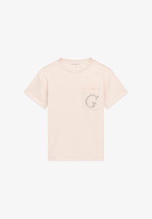 Hellbeiges T-Shirt mit kurzen Ärmeln und Rundhalsausschnitt, vorne mit einer Tasche, die ein dekoratives, mit Schmucksteinen besetztes "G" auf der linken Brust zeigt.