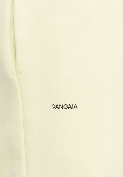Cream-colored fabric with a small black "PANGAIA" logo embroidered near a pocket seam.