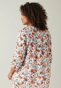 Bluse med blomsterprint i let stof, der har orange, blå og hvide farver, med trekvartærmer og en afslappet pasform.