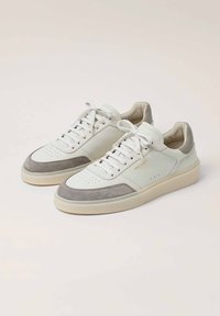Sneakers bianchi in pelle con accenti in suede grigio, punta rotonda, tomaia perforata, lacci piatti e suola in gomma testurizzata. Design minimalista.