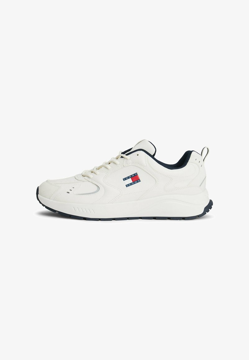 White athletic shoes with a textured leather upper, navy accents, logo patch on the side, and a cushioned sole for comfort.