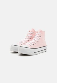 High-top sneakers in soft pink canvas with white eyelets and laces. Rubber toe cap and textured white sole with black accent line.