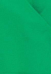 Green textured fabric with a slightly raised, diamond-patterned surface, featuring a soft feel and vibrant color.