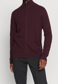 Vínový svetřík na zip s vysokým límcem, dlouhými rukávy a žebrovanými manžetami a lemem. Vyrobený z měkké látky, navržený pro přiléhavý vzhled.