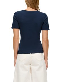 Marineblauwe geribbelde t-shirt met korte mouwen, gegolfde zoom en halslijn. Gekoopt met off-white, wijde broek, die een aansluitende silhouet toont.