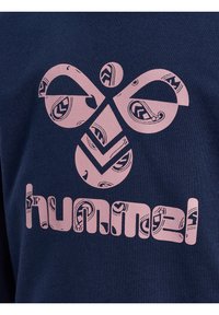 Dunkelblaues Sweatshirt mit einem großen, hellrosafarbenen Grafikdesign mit aufwendigen Mustern und dem markant dargestellten Markennamen "hummel".