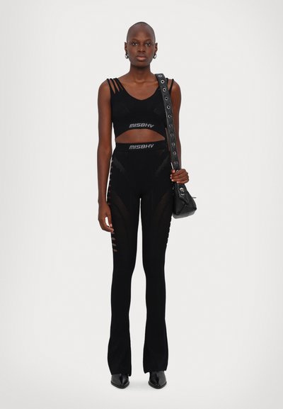 Musthave musta lühikeste varrukatega top külje lõigetega ning sobivad kõrge vöökohaga legginsid lõigatud detailidega, koos väikese musta kotiga ja kontsakingadega.