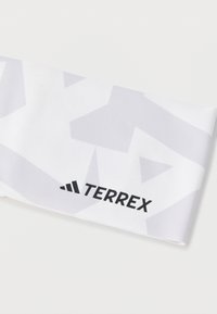 Vitt tygpannband med ett geometriskt grått mönster. Har en svart "TERREX"-logotyp på ena sidan. Mjuk textur, lämplig för idrottsbruk.
