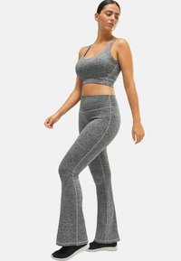 Conjunto atlético gris que incluye un top recortado y leggings acampanados. La tela presenta una textura jaspeada con costuras en contraste y un diseño ajustado.