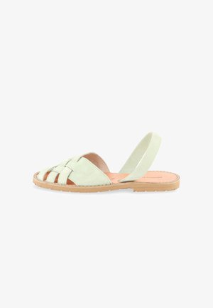 Lichtgroene platte sandaal met geweven voorstraps, open teen en een elastische achterriem op een beige rubberen zool.