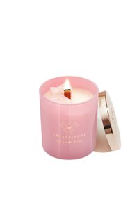 Różowy szklany świecznik z złotą pokrywką, zawierający palącą się knot z kryształami na wierzchu. Etykieta mówi "CRYSTALLOVE: różowy kwarc i róża."