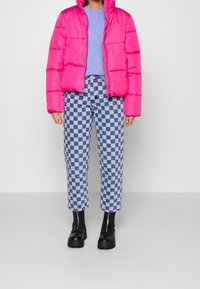 Rosa puffjacka, ljusblå tröja, rutiga byxor i blått och vitt samt svarta klumpiga ankelstövlar. Texturerade material, djärva färger.