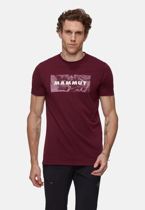 Bordeaux t-shirt met korte mouwen, gemaakt van katoen, met een groot, textured "MAMMUT" logo aan de voorkant tegen een gemarmerde achtergrond.