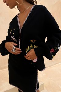Čierny pletený cardigan s kvetinovou výšivkou v farbách ako žltá, červená a zelená. Dizajn s výstrihom do V, kontrastným ružovým lemem a voľnými rukávmi.
