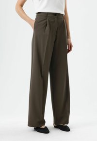 Wide-leg trousers in dark olive green fabric with front pleats, side pockets, and a single button fastening at the waist.